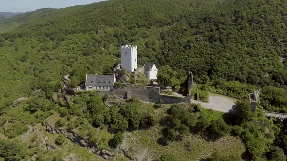 Drone Flight aroung medieval castle in a forest on a mountain at a river.