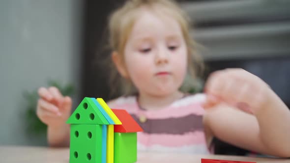 a Cute Little Girl Builds Houses From a Colorful Wooden Construction Set