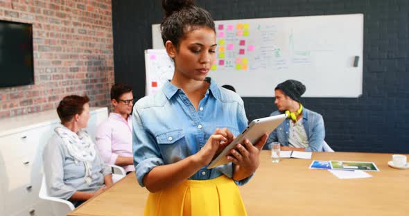 Businesswoman using digital tablet while coworkers interacting with each other