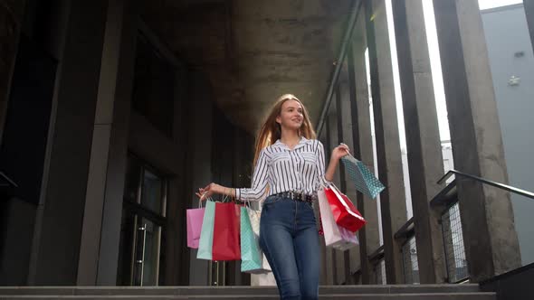 Smiling Girl Walking From Centre Mall with Shopping Bags, Happy with Purchase on Black Friday