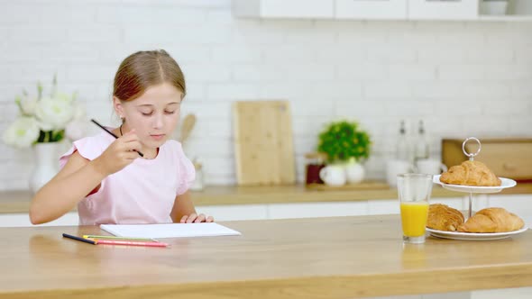 Girl Draws While Sitting in the Kitchen