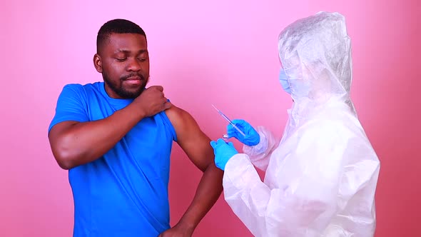 African American Man Scientist in PPE Suite Uniform Showing Medicine Liquid Vaccine Vial Bottle