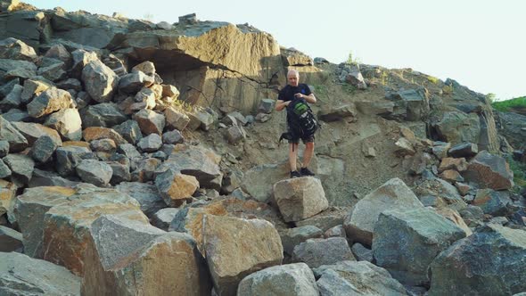 traveler with a backpack in shorts and a black t-shirt is sitting on a large rock