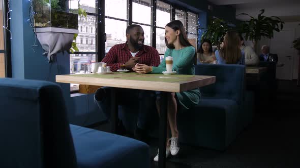 Laughing Couple Holding Hands in Coffee Shop