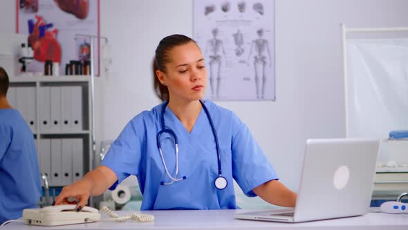 Woman Nurse Answering Telephone in Hospital Reception