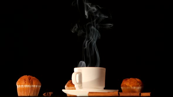 White Steaming Coffee Cup with Cakes, Anise, Cinnamon on Black Background