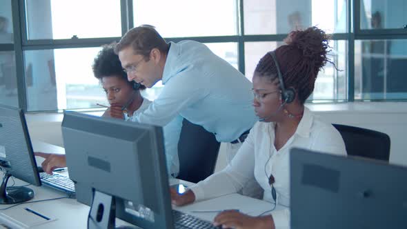 Male Manager Helping Call Center Operators New Software