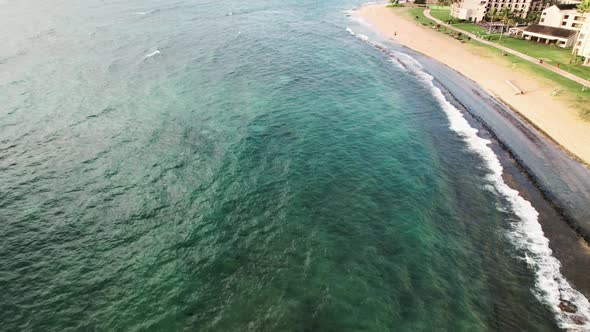 Flying south along the east coast of Kauai, Hawaii, clear aqua green waters golden sand beach, aeria