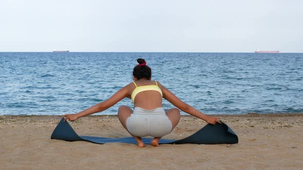 Yoga woman practices yoga and meditates in lotus position on beach sea. Healthy female