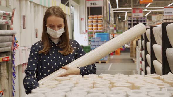 A Woman in a Protective Mask Buys Wallpaper at a Hardware Store