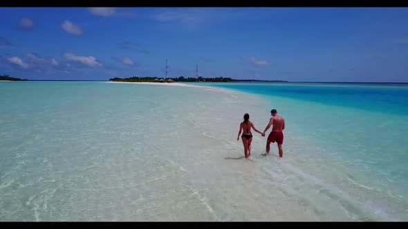 Teenage lovers tanning on tranquil resort beach break by blue ocean and white sandy background of th