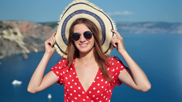 Smiling Young Woman in Sunglasses Holding Straw Hat By Hand Posing at Natural Sea Background