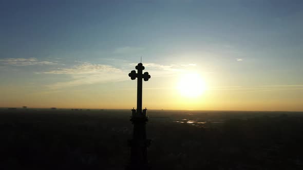 An aerial shot of a cathedral's steeple, taken at sunrise. The camera track left and pan right orbit