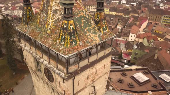 A drone shot, with panning and trucking motion combined, capturing the Sighisoara Clock Tower on an