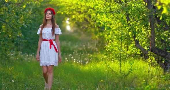 Beautiful Young Woman in a White Dress Walks Through a Forest Glade She is Happy