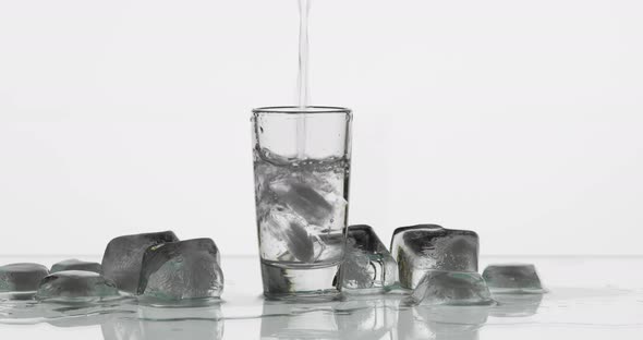 Pouring Up Shot of Vodka From a Bottle Into Glass. White Background