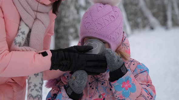 Mother Giving Hot Tea To Her Child in Winter Park