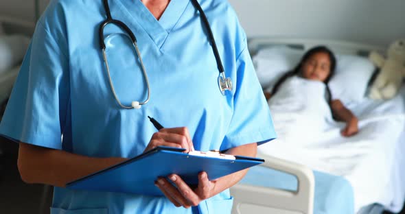 Female doctor writing on clipboard