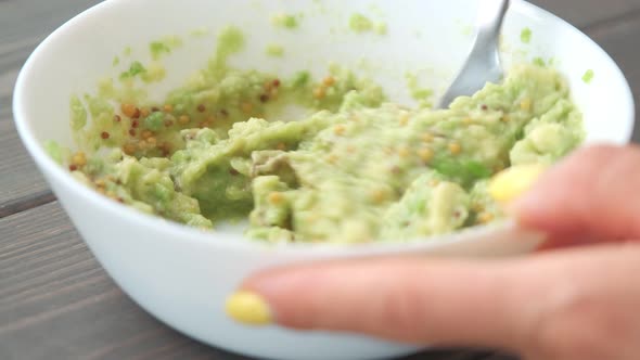 Hands Mashing Avocado in Bowl with a Fork