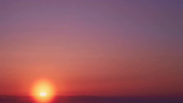 Sunrise among beautiful clouds. Orange sun in the morning sky, timelapse