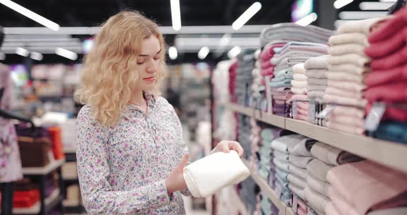 Young Woman Chooses Towel in a Supermarket