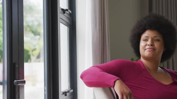 Video of happy plus size african american woman looking outside window