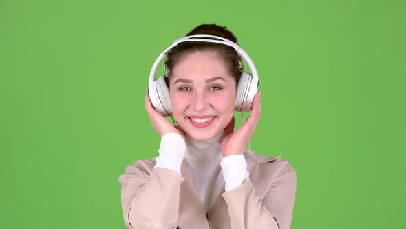 Woman Listens To Melodious Songs in the Headphones. Green Screen. Slow Motion