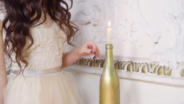 Young Brunette Woman in Long Evening Dress Plays with Candle