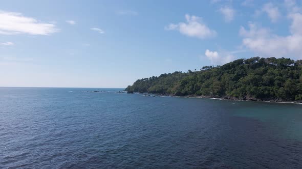 Approaching drone flight towards a lush tropical peninsula on Costa Rica's pacific shore.