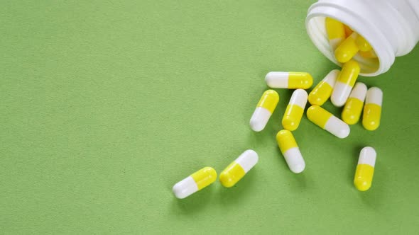 The pills are scattered on the table. Tablets on the green background
