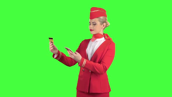 Stewardess Girl in a Red Suit Is Picking Up the Credit Card Code. Green Screen