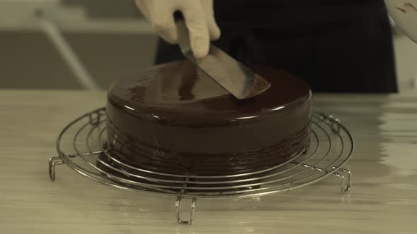 Professional chef moving the spatula over the chocolate glaze