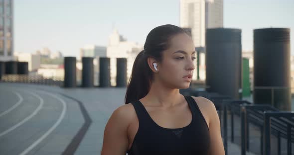 Portrait of Beautiful Young Athletic Woman Wearing Earphones Relaxing After Sport Training Standing