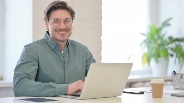 Middle Aged Man with Laptop Smiling at Camera