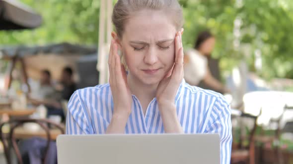 Tense Woman with Headache Using Laptop in Cafe Terrace