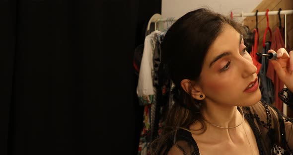 Young female applying mascara in front of mirror