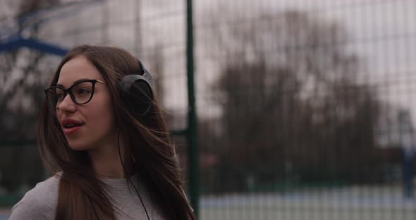 Cute Girl Walking in a Park Listening Music in Headphones