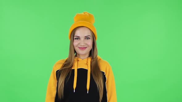 Portrait of Modern Girl in Yellow Hat Is Waving Hand Hi Then Blowing Kiss. Green Screen