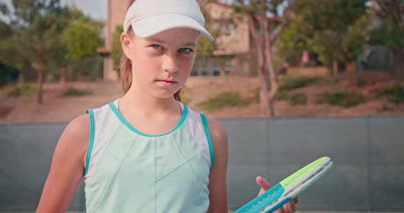 Female Tennis Player Mends Her Racket and Looks Into the Camera