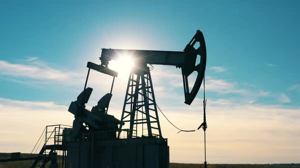 Silhouette of a Functioning Oil Pumpjack in an Oil Field