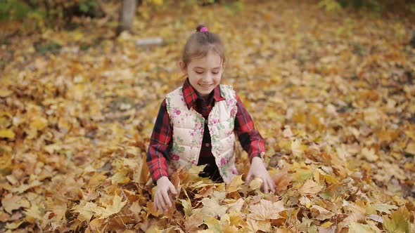 Happy Girl Accelerates and Jumps Into a Big Pile of Foliage and Laughs