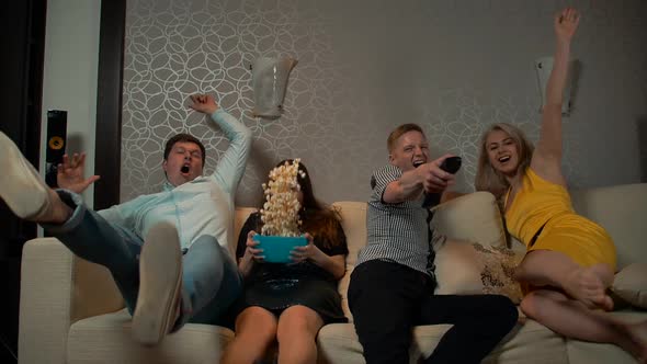 Young People Falling Down on Sofa To Watch TV with Pop Corn