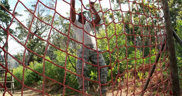 Military soldier climbing rope during obstacle course