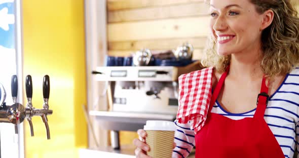 Smiling waitress serving a coffee to customer at counter