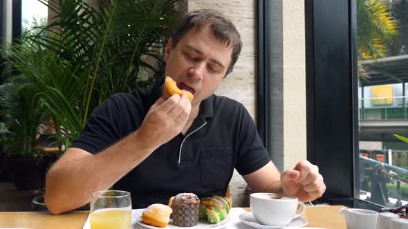 Happy Man Enjoy Brekfast Eat Sweet Donut Bun Chewing Sit in Restaurant Cafe