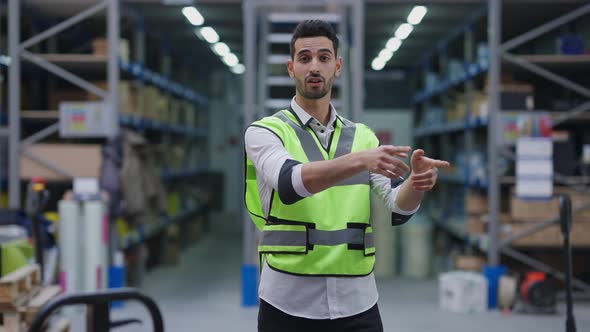 Portrait of Professional Middle Eastern Expert Talking Pointing at Cargo on Racks in Warehouse