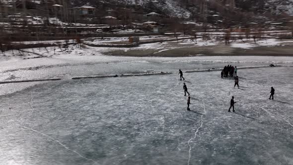 Aerial Over Silhouette Of Ice Hockey Players On Frozen Khalti Lake At Ghizer Valley. Circle Dolly