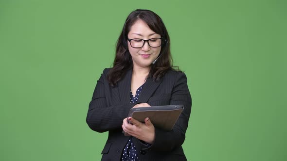 Mature Beautiful Asian Businesswoman Working As Call Center Representative and Using Digital Tablet