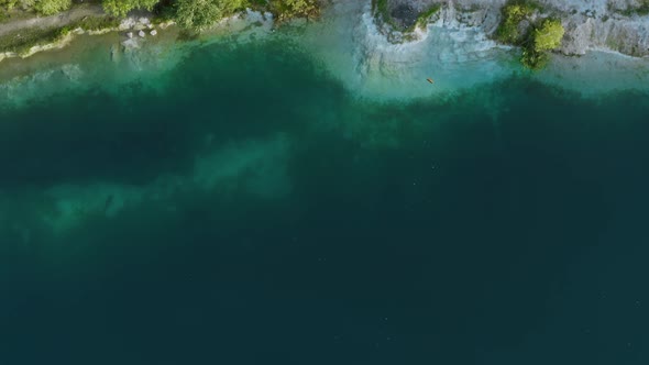 Aerial Top Down Flight Over Amazing Deep Lake Surrounded By Green Forest. Beautiful Lakeshore, Clean