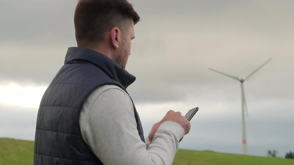 Male Engineer Makes Notes on Phone About Wind Turbine